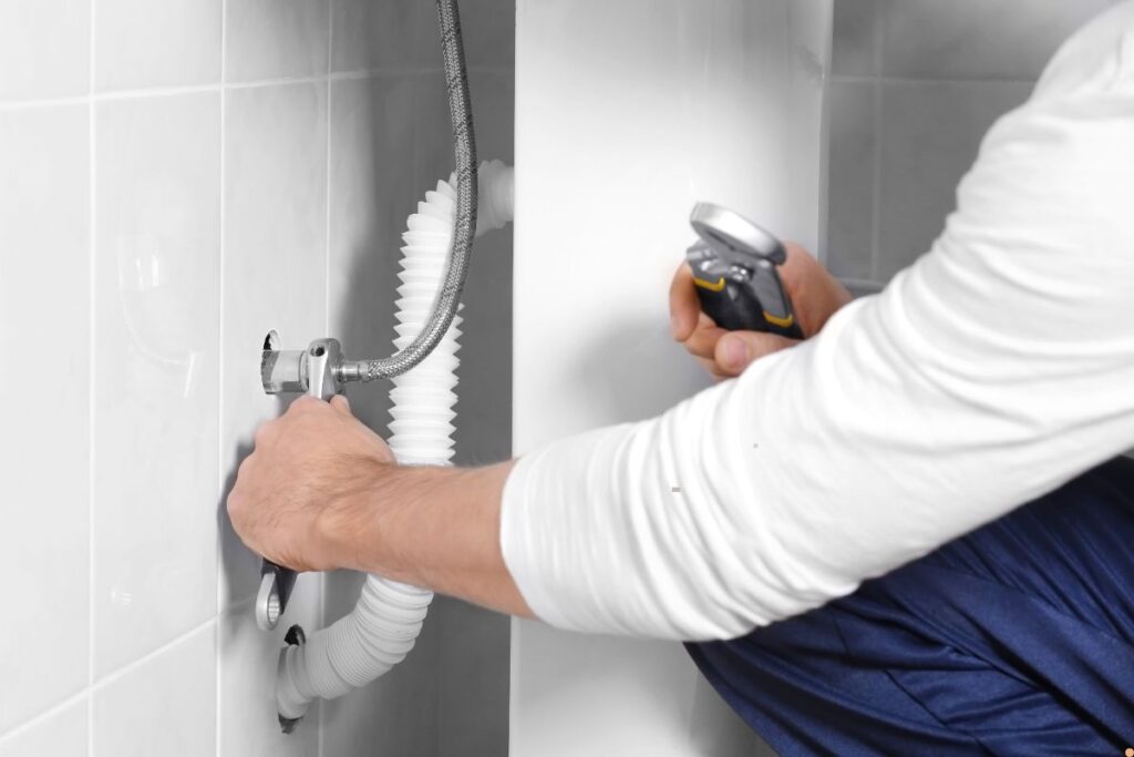 Plumber tightening a braided flexi hose connection under a bathroom sink. Albury Plumbing | Fletcher Plumbing and Co