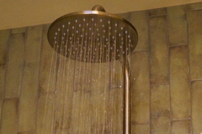 Ceiling mounted shower head with steady water flow in a tiled bathroom, showing modern plumbing fixture used in Albury Wodonga homes