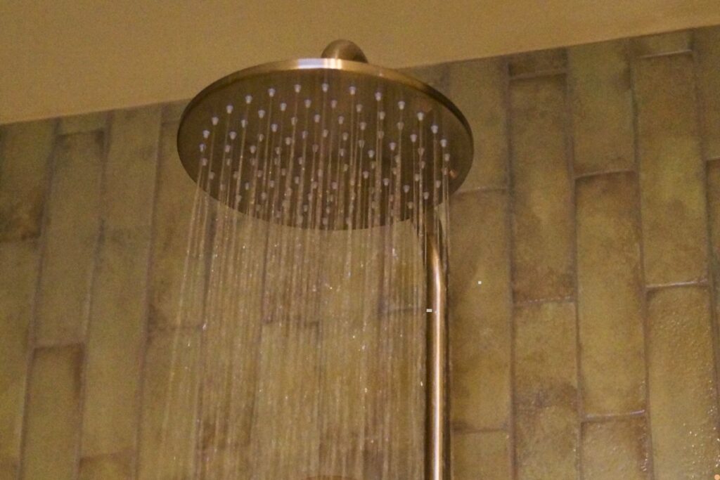 Large rainfall shower head running hot water inside a residential bathroom, highlighting a functioning hot water system during winter.