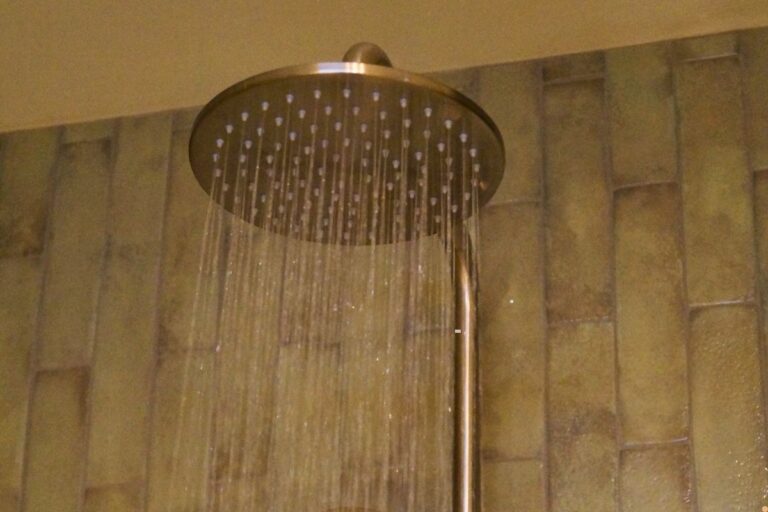 Large rainfall shower head running hot water inside a residential bathroom, highlighting a functioning hot water system during winter.